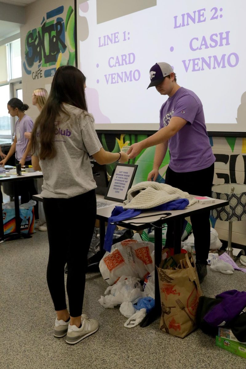 Checking out, junior Lilly Feuerborn hands money to Relay for Life committee member, sophomore Briggs Tomlinson. 