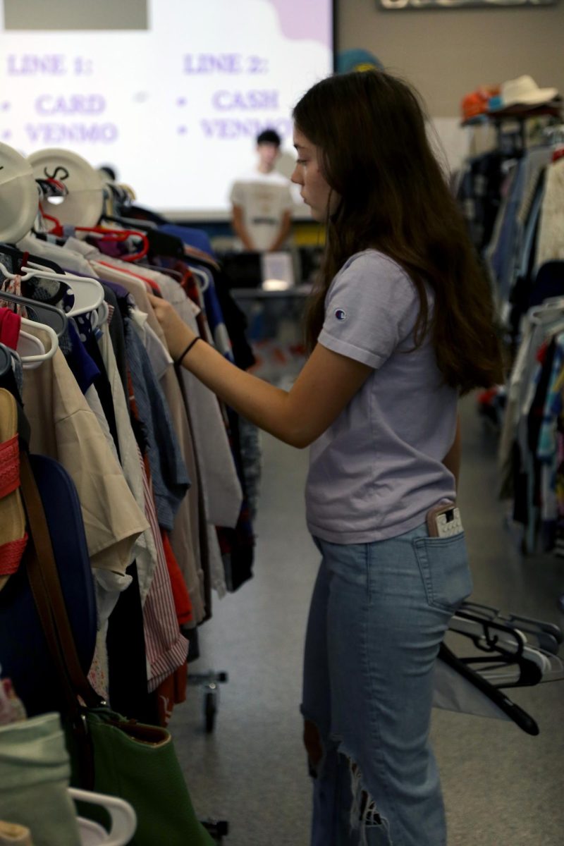 Straightening the clothes rack, senior Brooklyn Markovich organizes the women's shirts. 