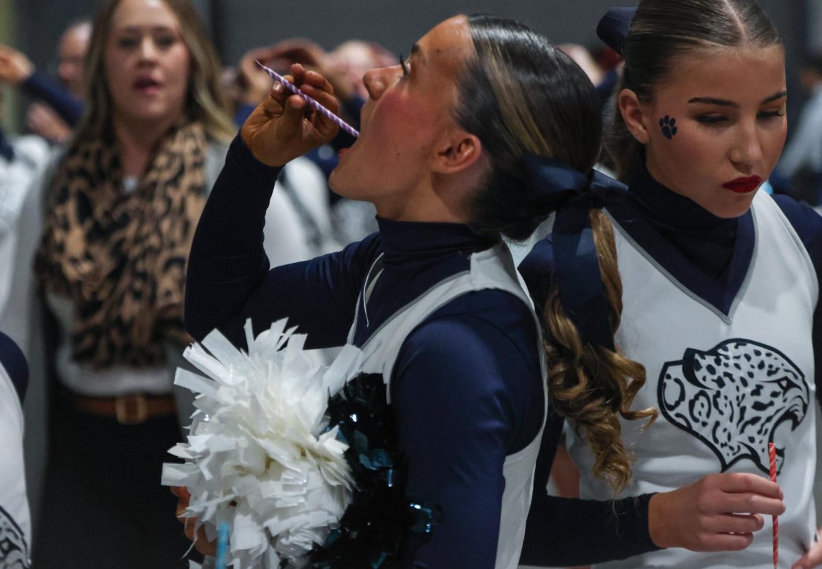 Tilting her head back, junior Rachael Johnston eats a pixie stick before the team takes the mat.
