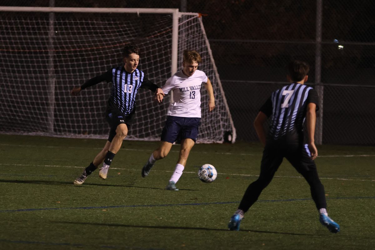 Moving around his defenders, senior Drew Enloe focuses on the ball and keeps it under control.