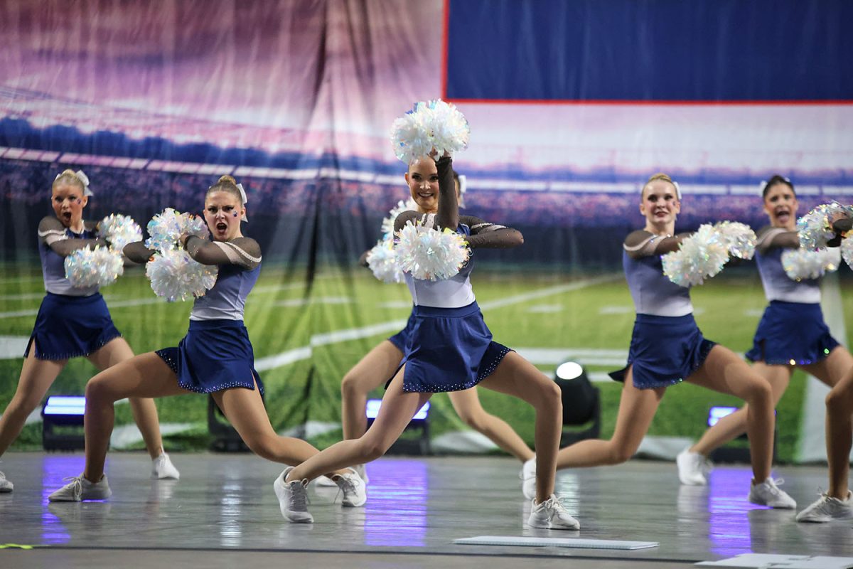 In the middle, junior Bailey Bret pauses with her poms in the air while dancing on the KSHSAA stage. 