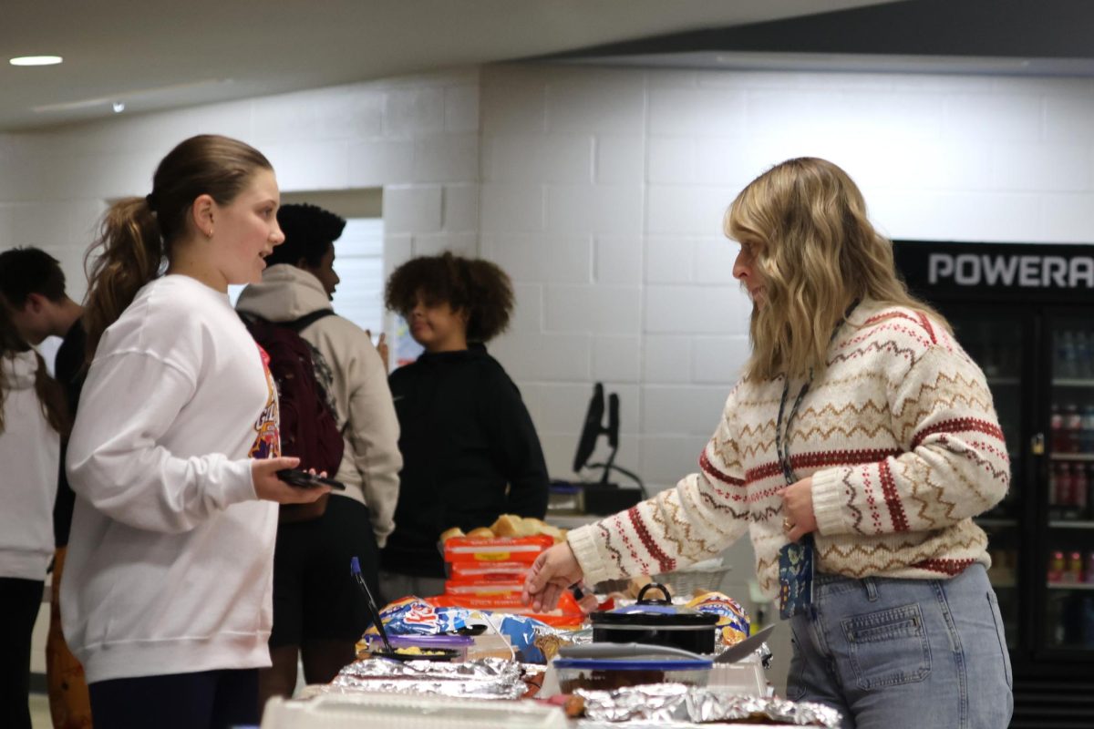 Freshman Ava Munsey and English teacher Malorie Waller discuss how to organize the different foods brought to Clubsgiving by the different clubs.