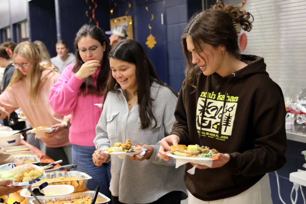 Seniors Celeste White and Lily Folendore fill their plates with all of the different options at Clubsgiving.