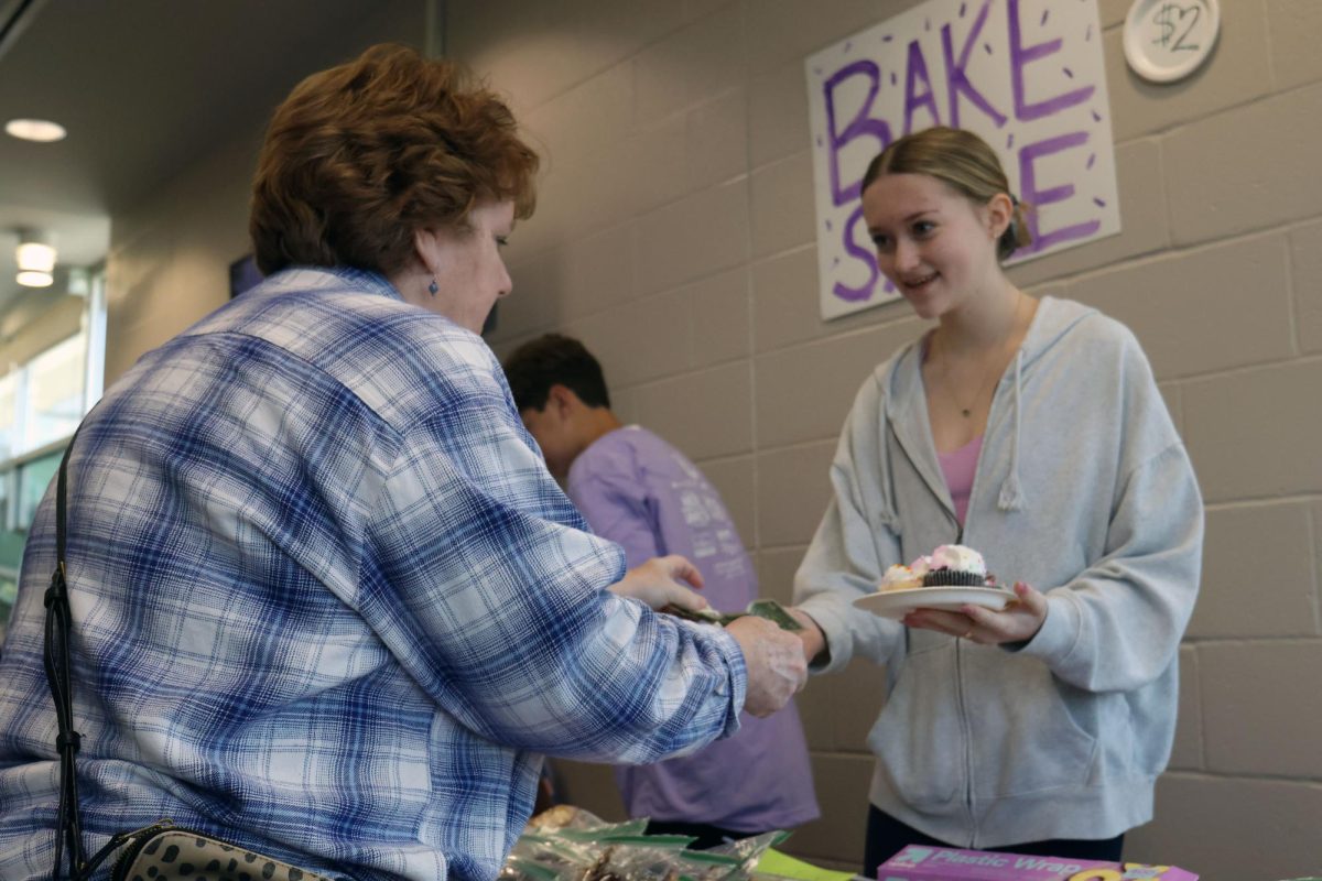 Cupcakes in hand, sophomore Layla Land checks out a customer at the bake sale.