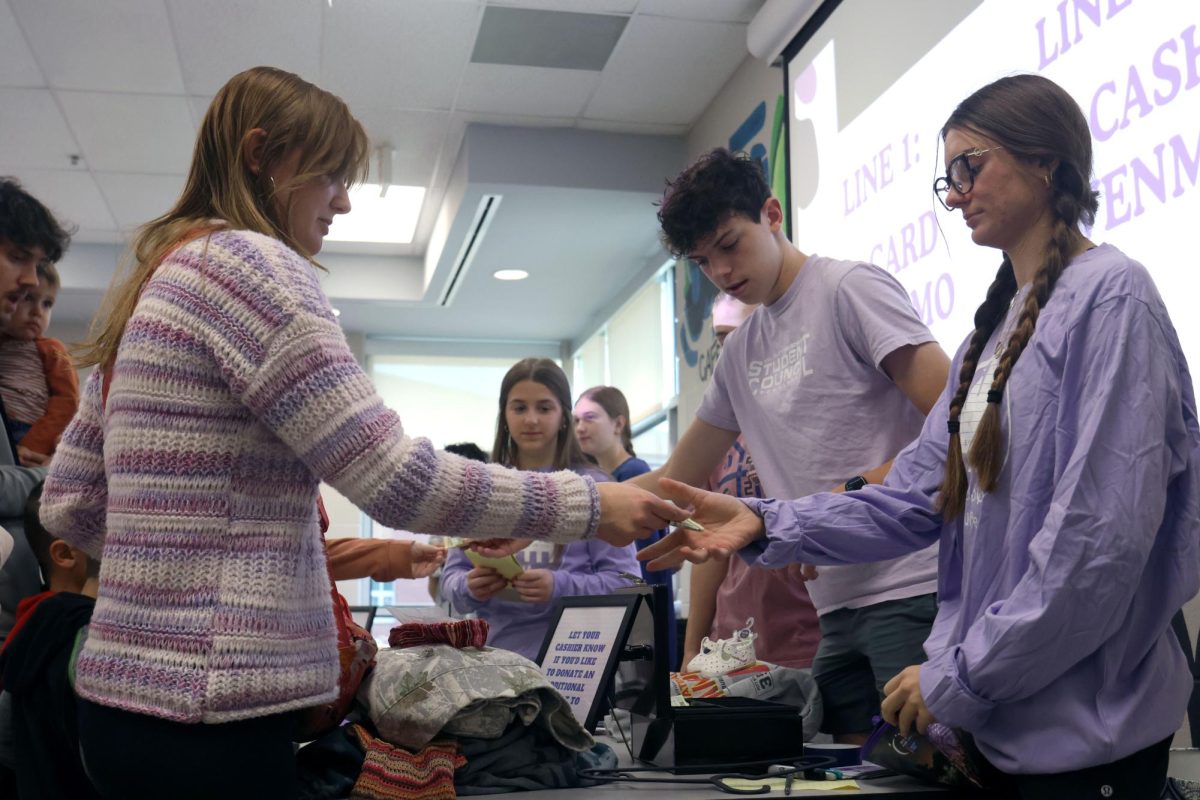 Helping a customer, senior Seville Skinner takes money from the shopper.