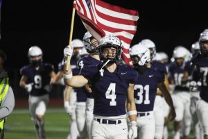 Carrying the American flag, senior Garret Clark leads the team out. 