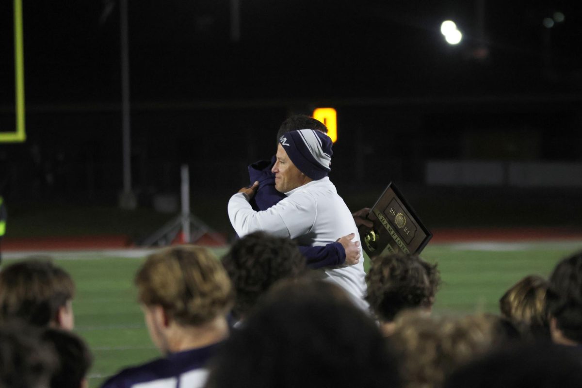 Coach Joel Applebee and athletic director Brent Bechard hug as the regional champion plaque gets passed on. 