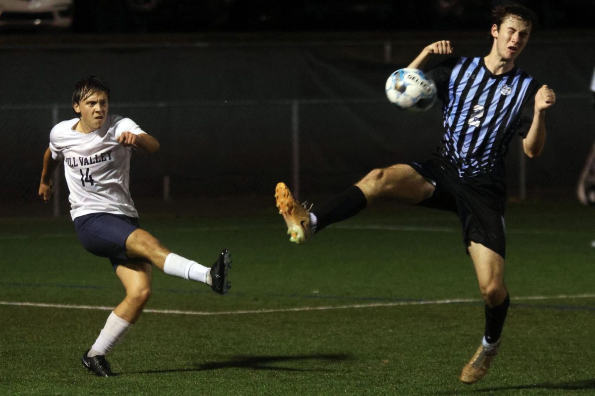 Senior Kai Burford kicks the ball as defender attempts to block it. 