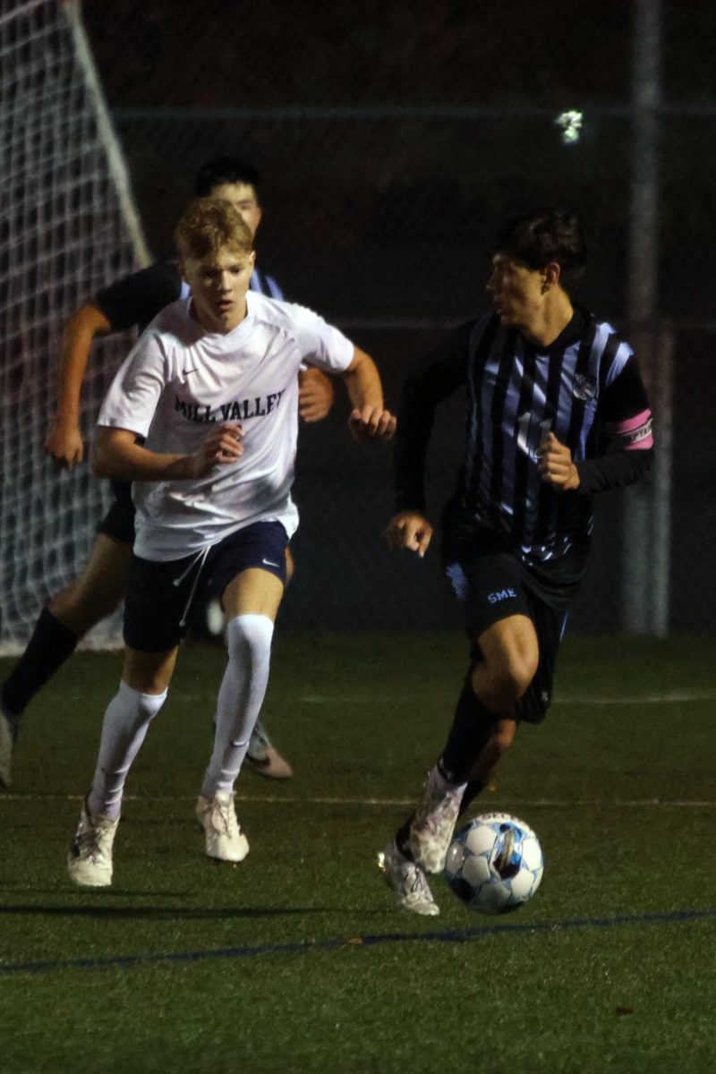 While side to side with a defender, junior Ayden Kostus dribbles the ball. 