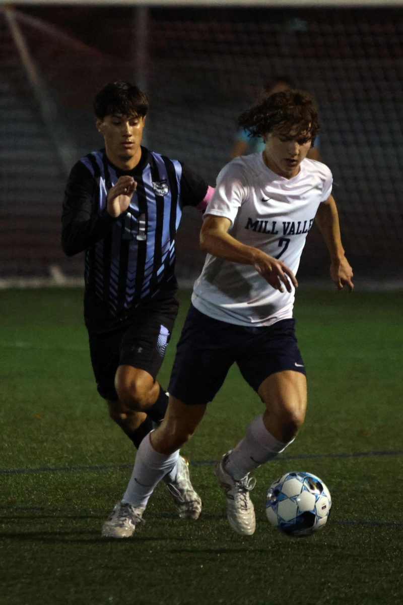 Junior team captain Landon Vincent dribbles the ball with defender trailing closely behind him. 