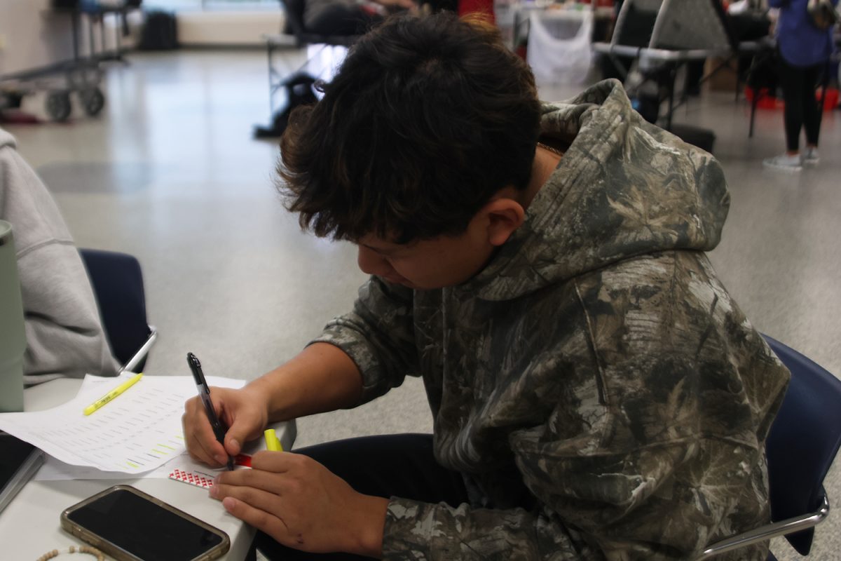 Pen in hand, sophomore Josh Garcia writes a donor's name on a name tag.