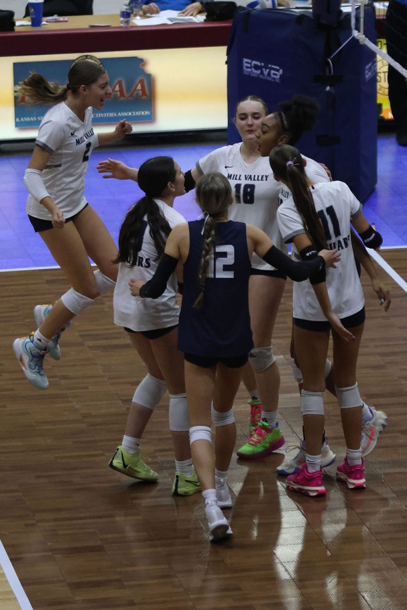 The team huddles together in excitement after winning a point against Olathe West.