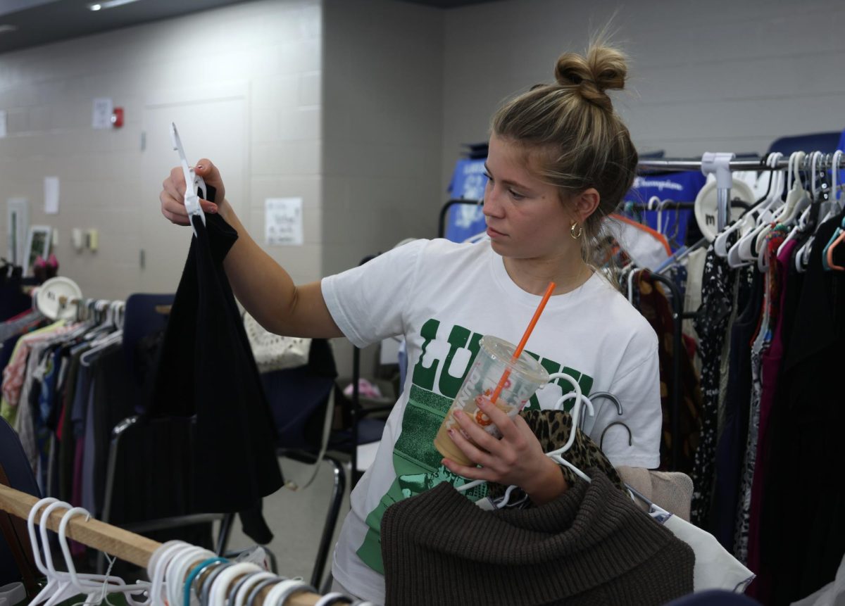 While looking at clothes, sophomore Peyton Heinrich buys items while thrifting.