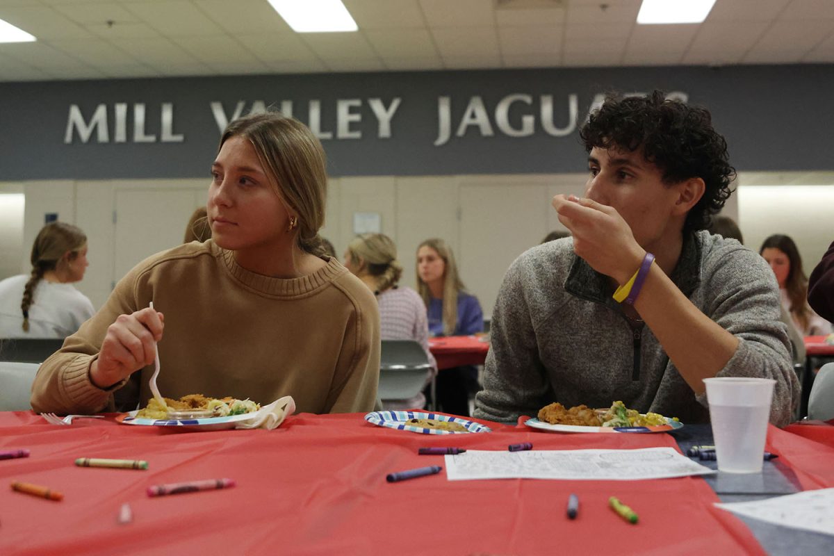 Looking at their friends, juniors Kate Dresvyannikov and Max Fierro sit together.
