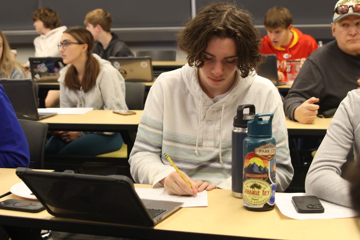 Finding the answers, junior Ethan Culver writes down the penalties for the rules worksheet on Thursday, Dec.12.