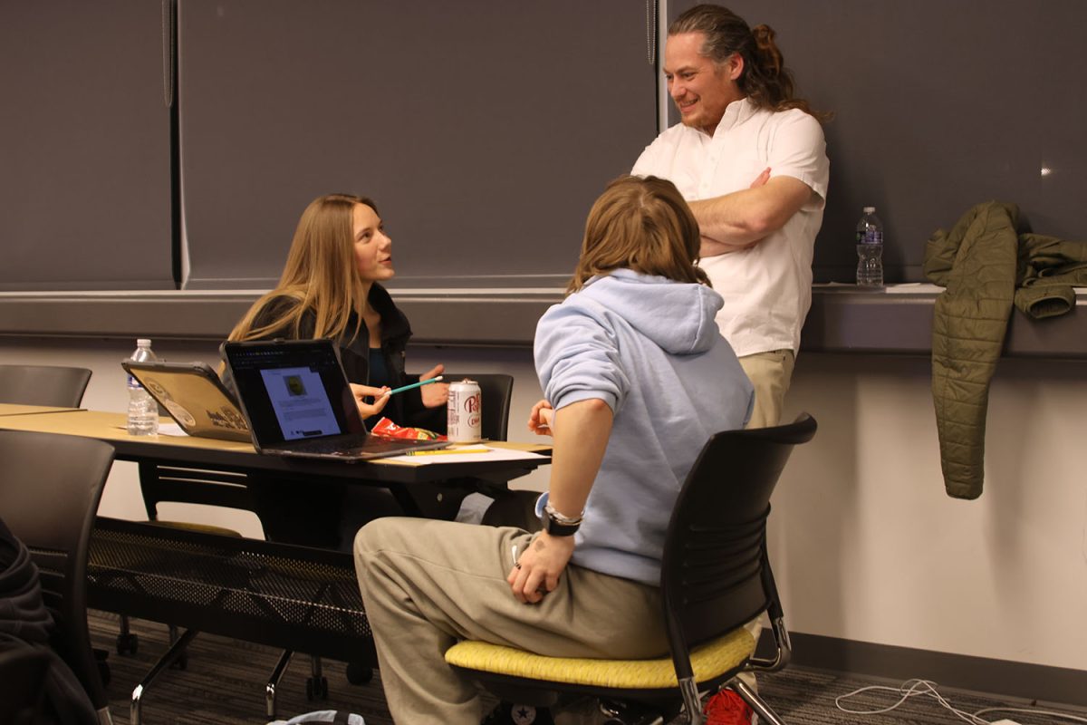 Talking to Neil McLeod, sophomore Aurora Straight and senior Ellery Wilson takes a break from working on their rules worksheet.