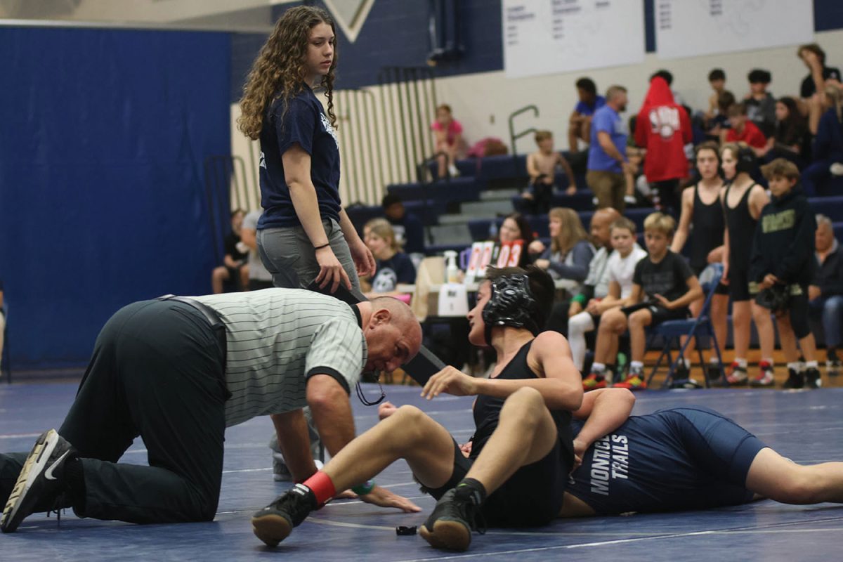 Watching the middle schoolers wrestling moves, senior Laiyah Kirkpatrick helps the ref know when the match times up, Thursday Nov. 7.
