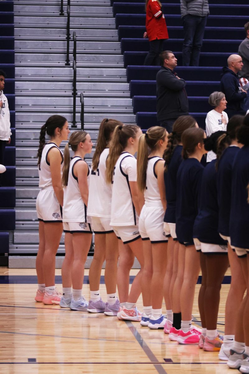 The team stands ready, listening to the National Anthem prior the the game beginning. 