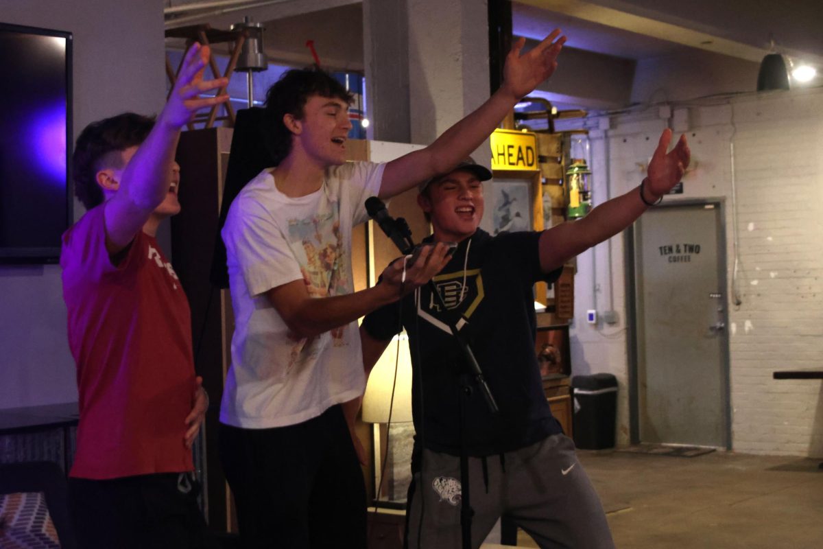 Juniors Gavin Hurt, Reece Riedel and Elliot Fischer reach their arms out while they perform karaoke to "Unwritten."