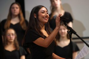 Holding the microphone, sophomore Azaria Vazquez introduces the next song. 