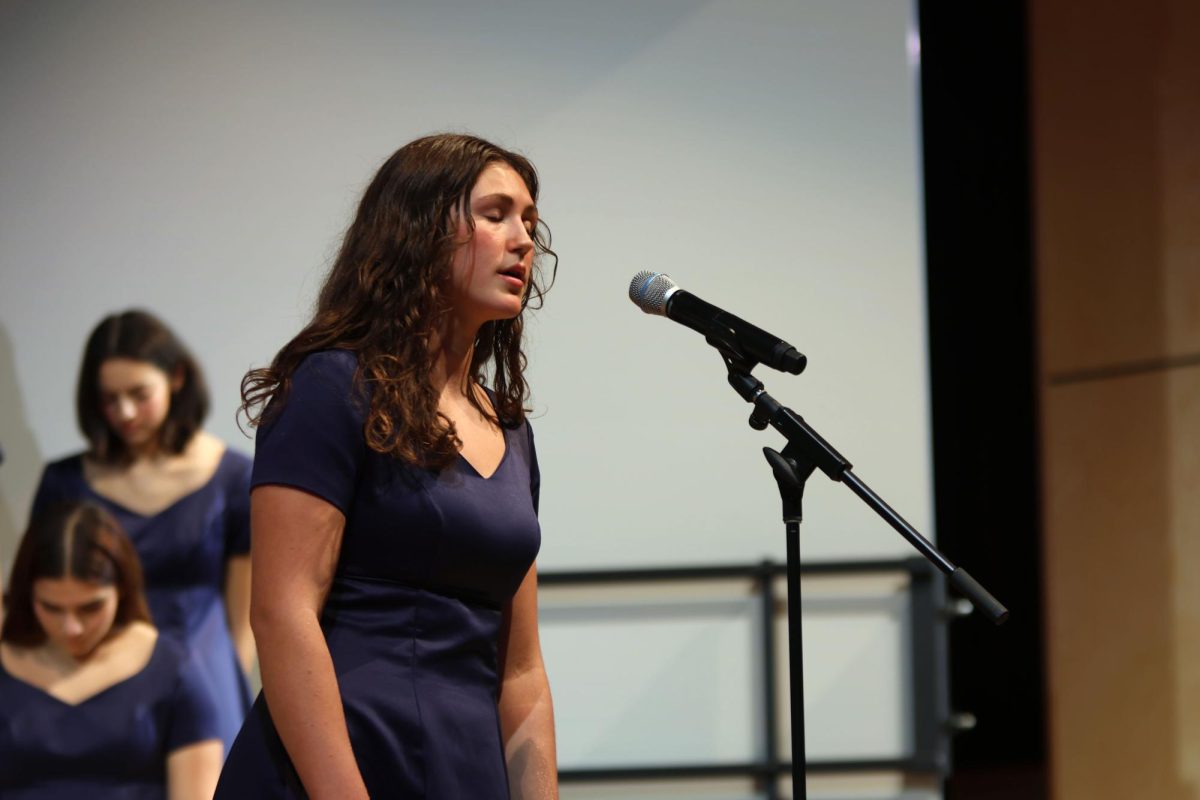 Singing into the microphone, senior Lily Folendore performs her solo.