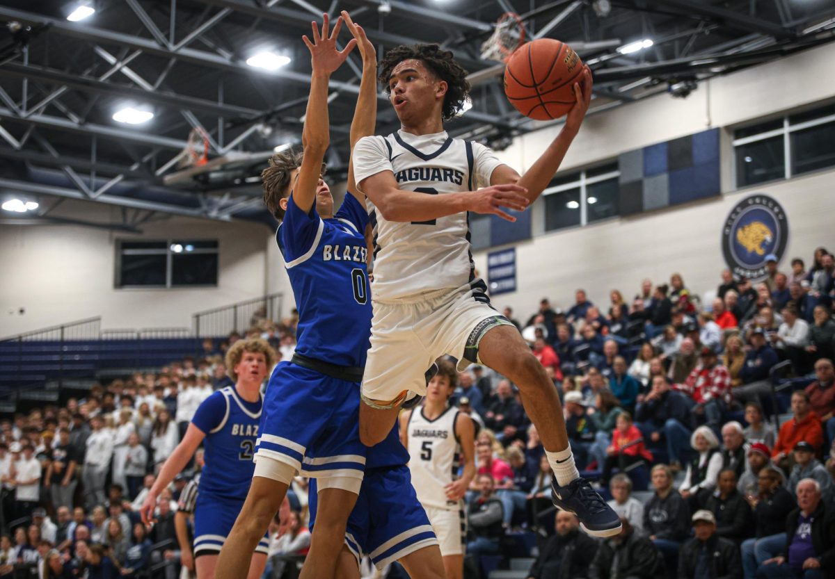 Scanning the court, junior JaKhai Carter makes a baseline pass while falling out of bounds