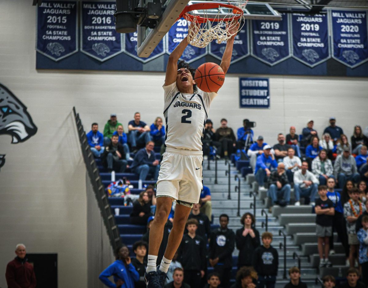 Yelling, junior Jakhai Carter celebrates his dunk as he hangs on the rim.