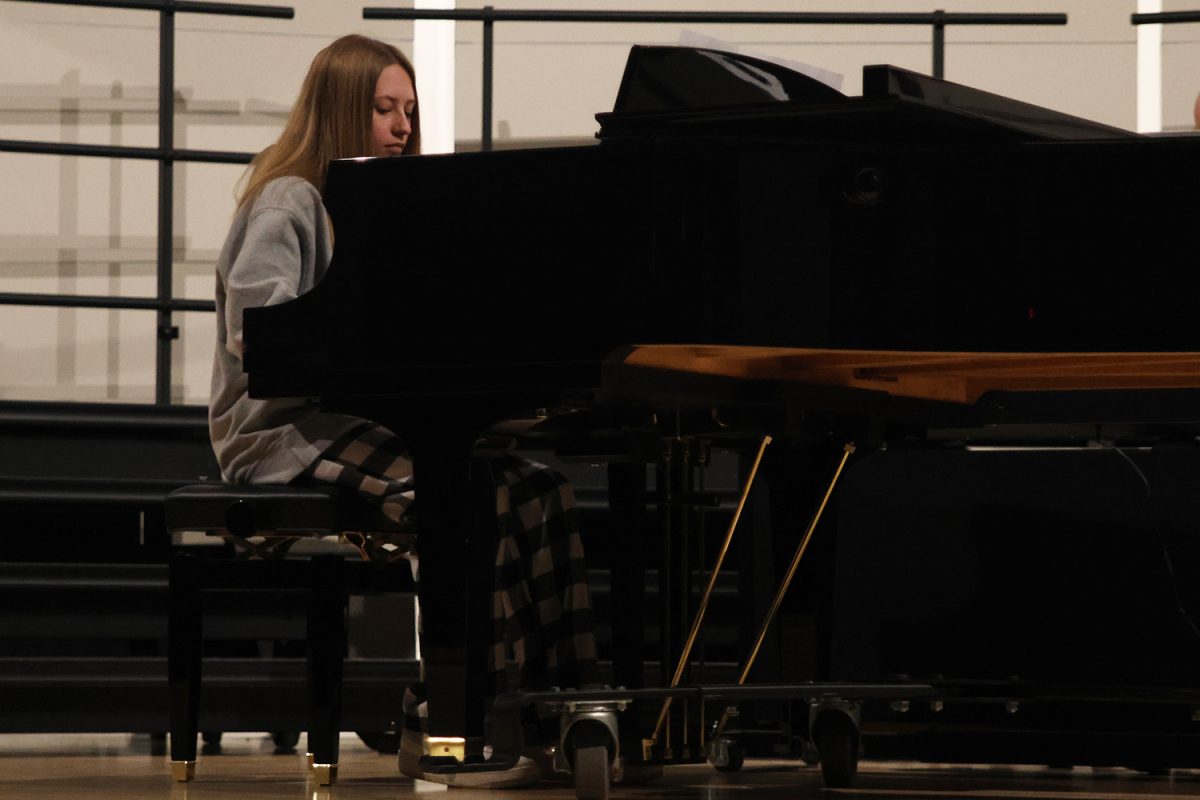 Focused, senior Molly Barhorst looks down at the keys while playing the piano.