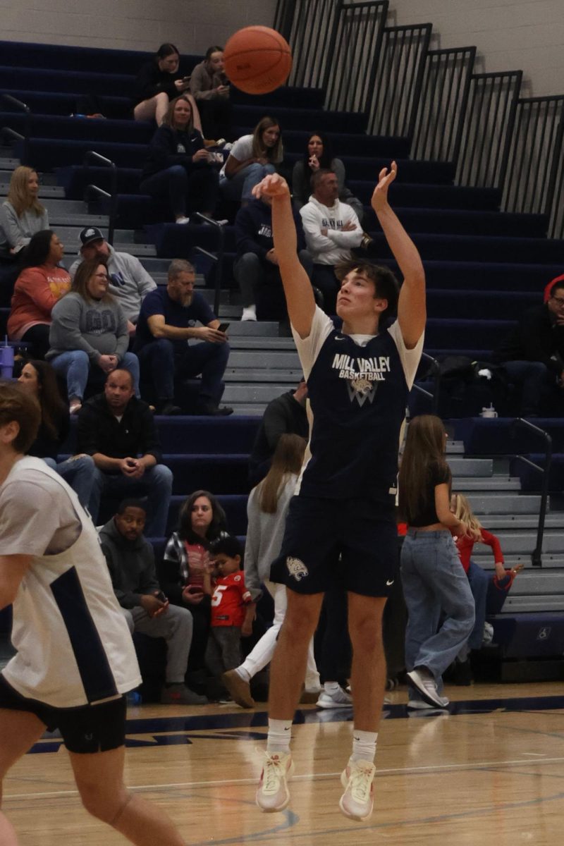 Sophomore Grady Larson shoots a basketball while warming up during the basketball scrimmage on Dec. 6. 