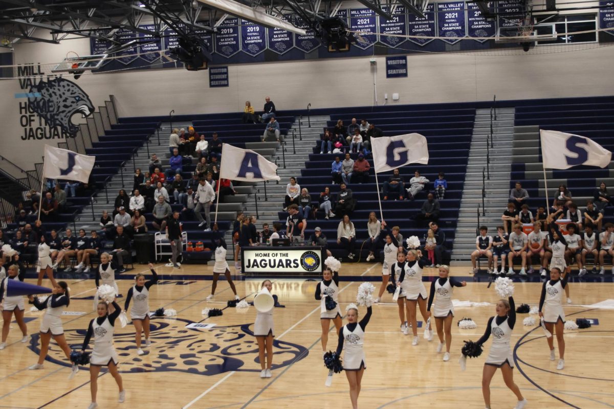 Cheerleaders twirl flags that create the word “JAGS” in the back of their routine as they perform a halftime show for the opening season basketball scrimmage on Friday, Dec. 6.  