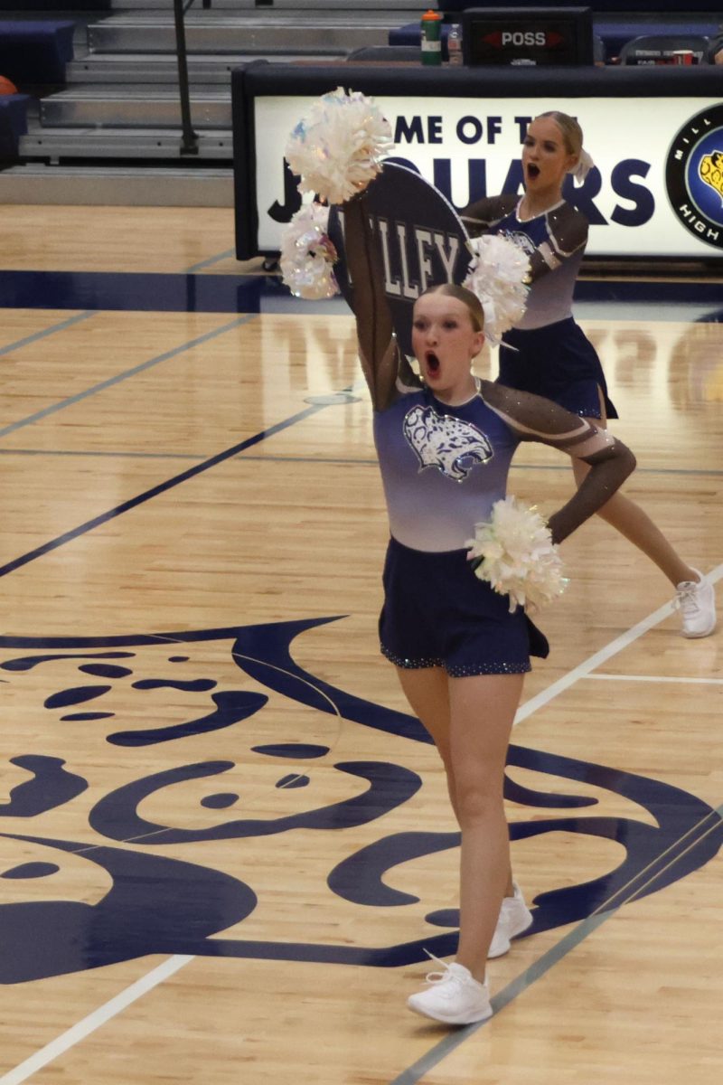 Raising a pom in the air sophomore Chloe Thomas dances as the Silver Stars show off part of their state competition performance during their halftime performance at the December 6th basketball scrimmage. 
