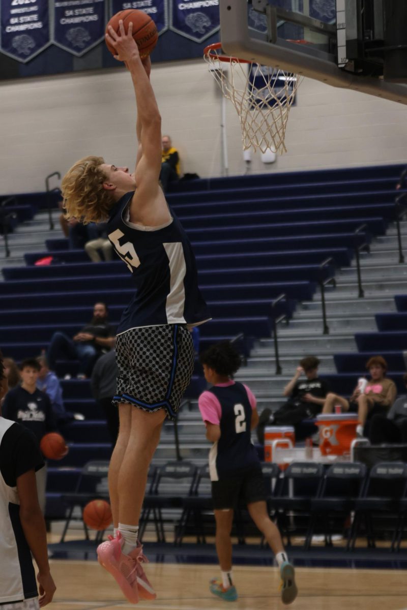 Junior Dylan Everhart dunks a basketball as the boy's basketball team shows off their skills during the opening season Basketball scrimmage on Dec. 6th. 
