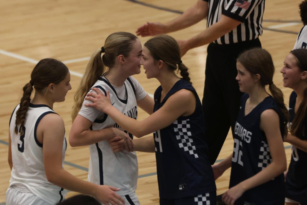 At the end of the game, sophomore Riley Marshall (white jersey) and senior Averie Landon (navy jersey) laugh as they shake hands and congratulate each other during the basketball scrimmage.   