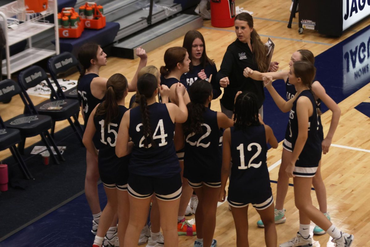 Coach _____ leads the team in a cheer after giving a pre-game speech during the basketball scrimmage on Friday, December 6th.