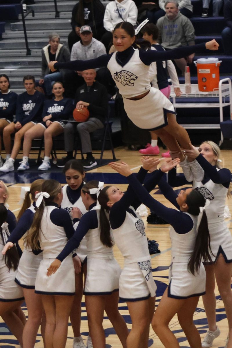 A stunt group of cheerleaders throws senior flyer Emersyn Jones into the air during their basketball scrimmage halftime performance. 