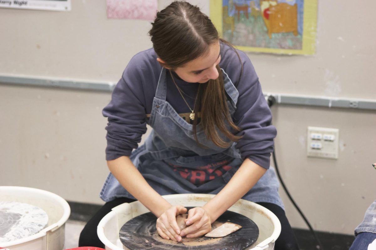 Smiling, sophomore Molly Gilmore works with her hands to shape her clay. 