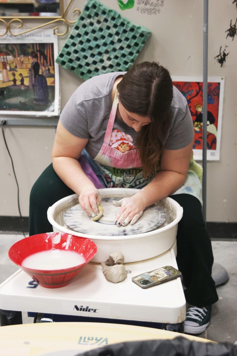 Junior Liberty Bouskil cleans up her work with a sponge and water while sitting at the wheel. 