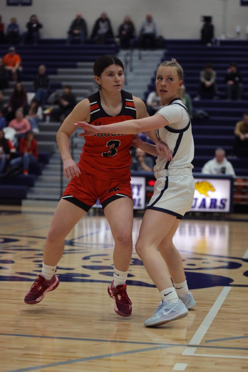 With her arm up, senior Josie Benson shields her opponent from getting the ball.