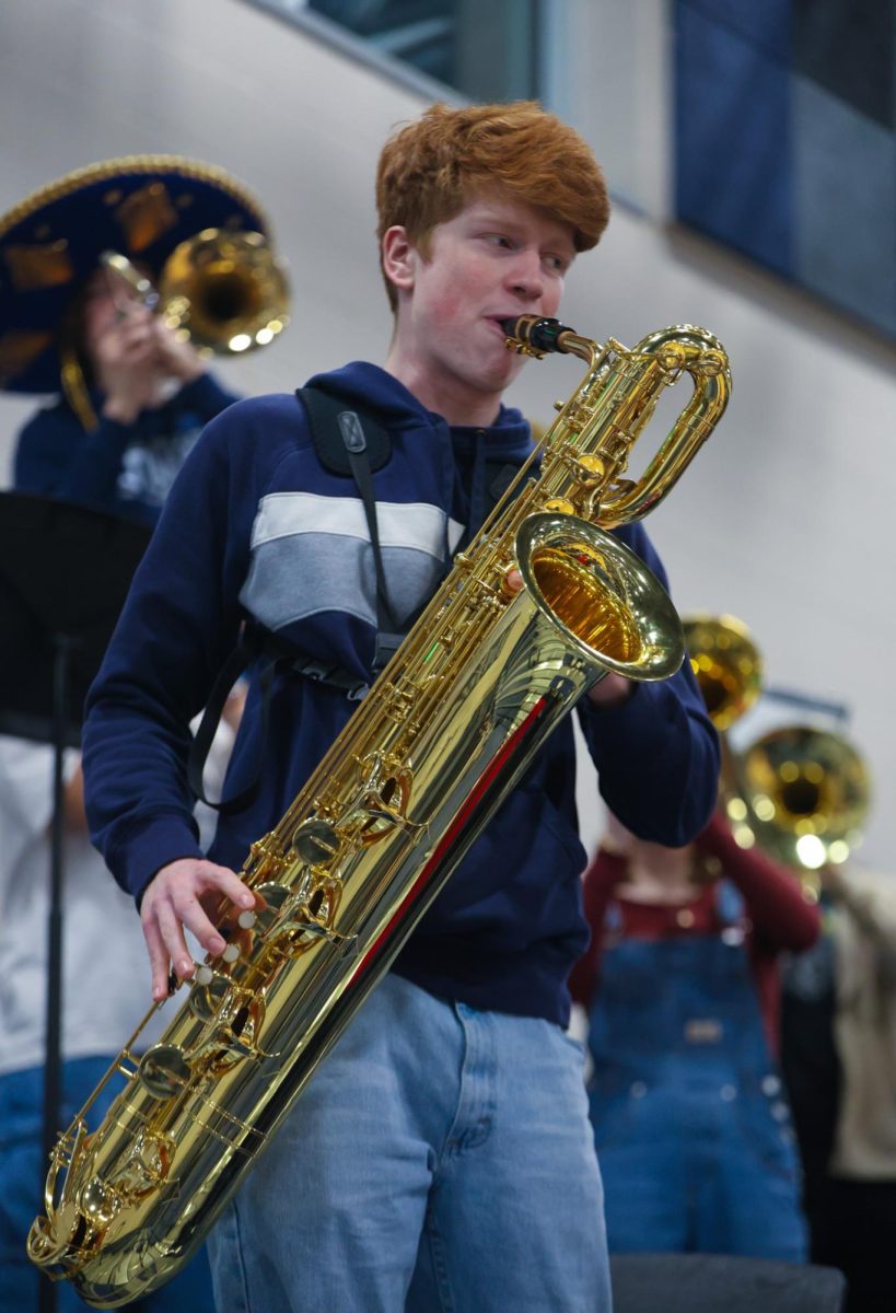 Looking at fellow bandmates, senior Brayden Evans plays the saxophone in tempo.  
