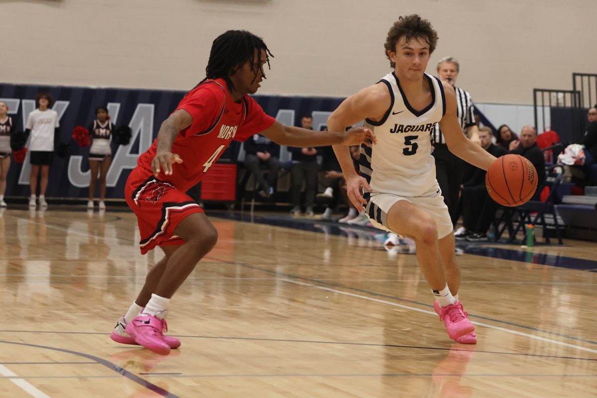 Running with ball in hand, junior Reece Riedel  tries to pass his opponent. 