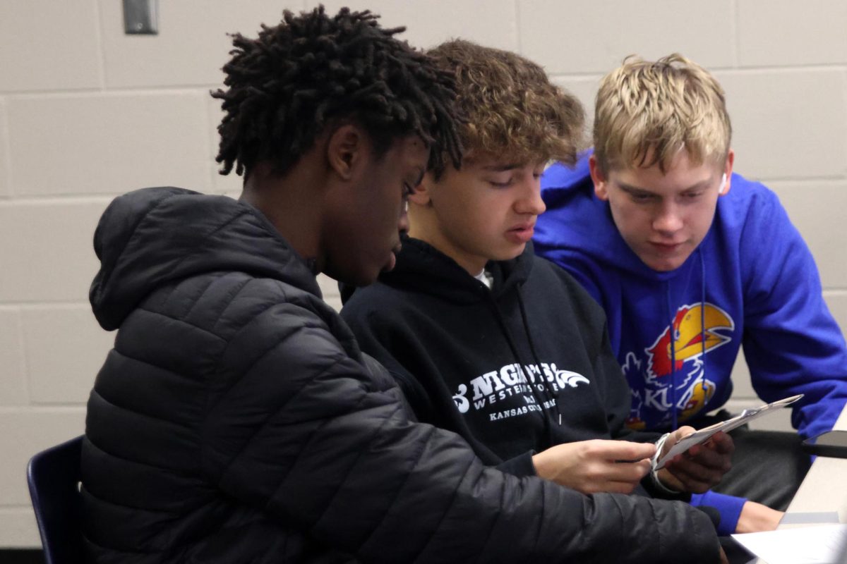 Freshmen Gabriel Lagat-Muttai, Ayden Brooks, and Carson Conner look at the design challenge together and make a plan on how to execute their different ideas.