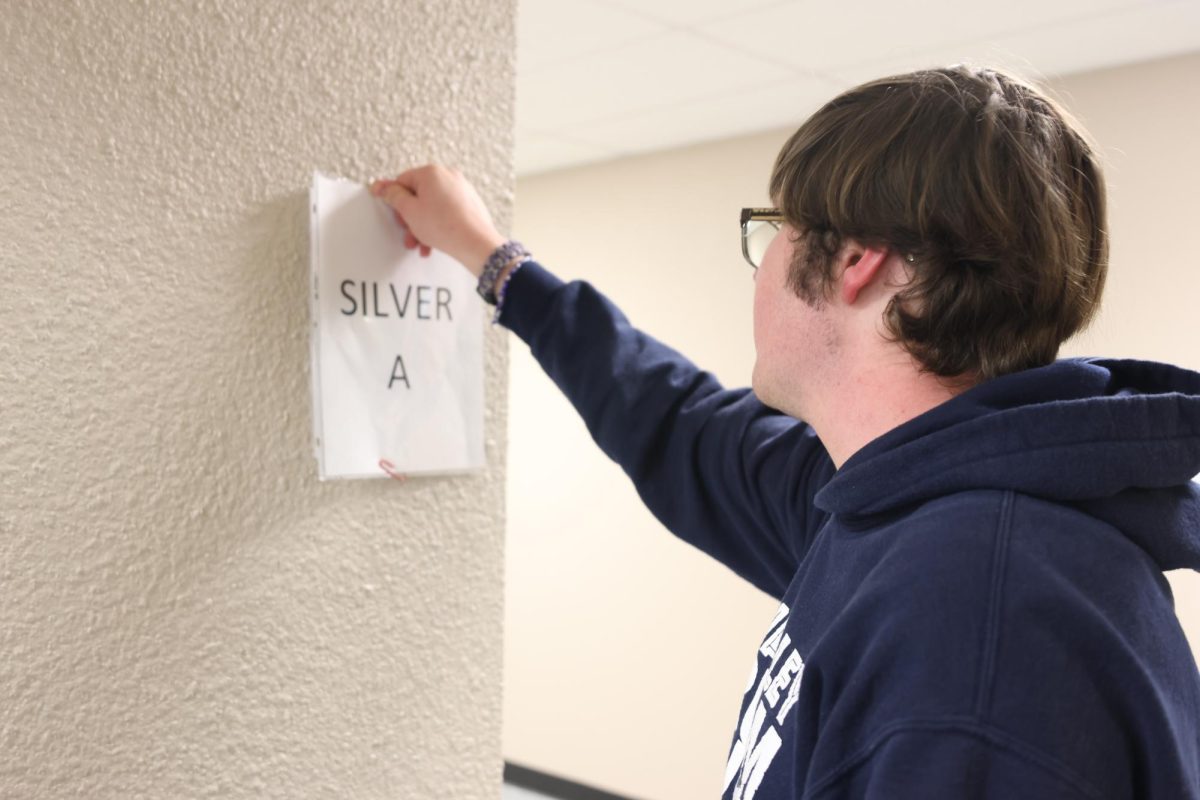 Junior Ian Weatherman tapes a sign outside room Silver A.