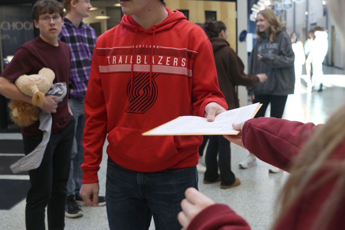 Junior Elaina Weese greets arriving teams at the main entrance.