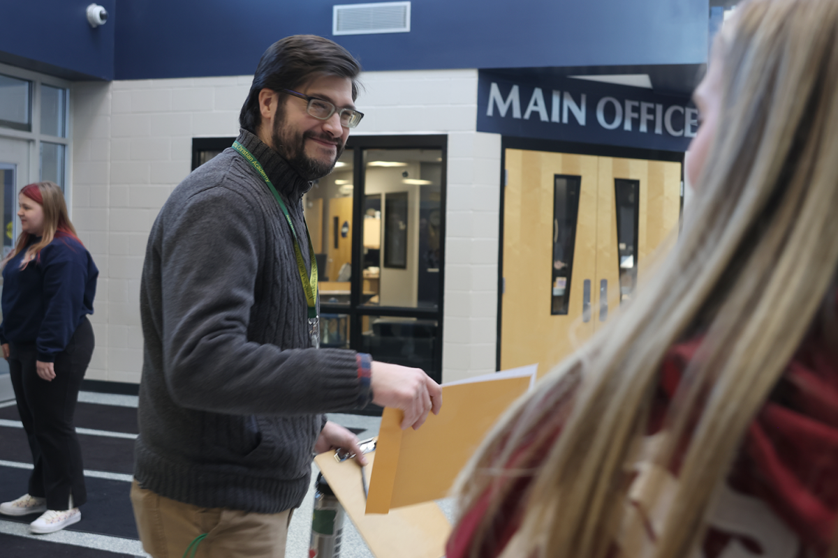 Junior Elaina Weese greets arriving teams at the main entrance.