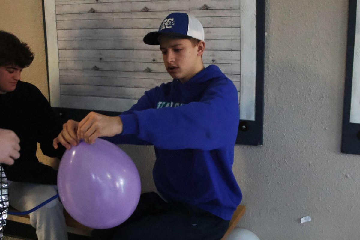 Sophomore Lucas Agre works on tying balloons to hand out to other Relay for Life members to decorate the school during Purple Bomb set up. 