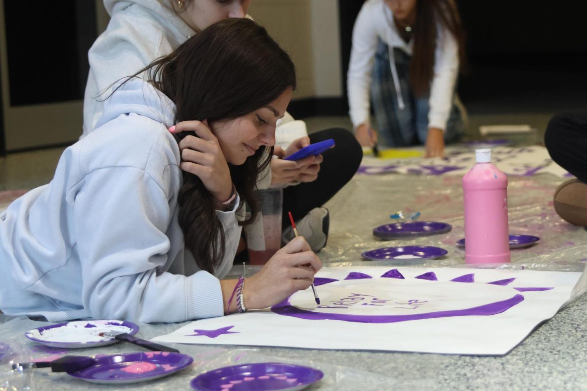 Junior Mallory Olson paints signs to decorate the halls during Relay for Life's Purple Bomb on January 20. 