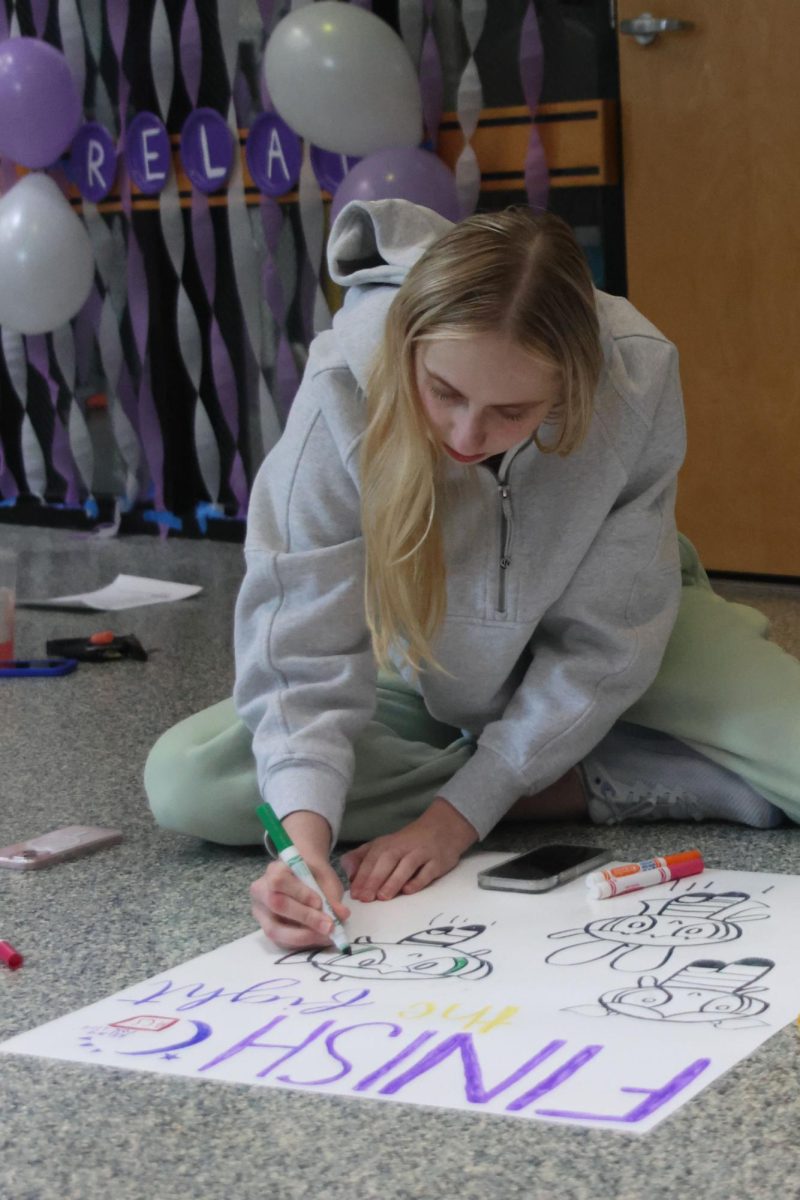 Senior Abigail Riggs works on coloring in a "Powerpuff Girls" themed Relay for Life poster for Purple Bomb. 