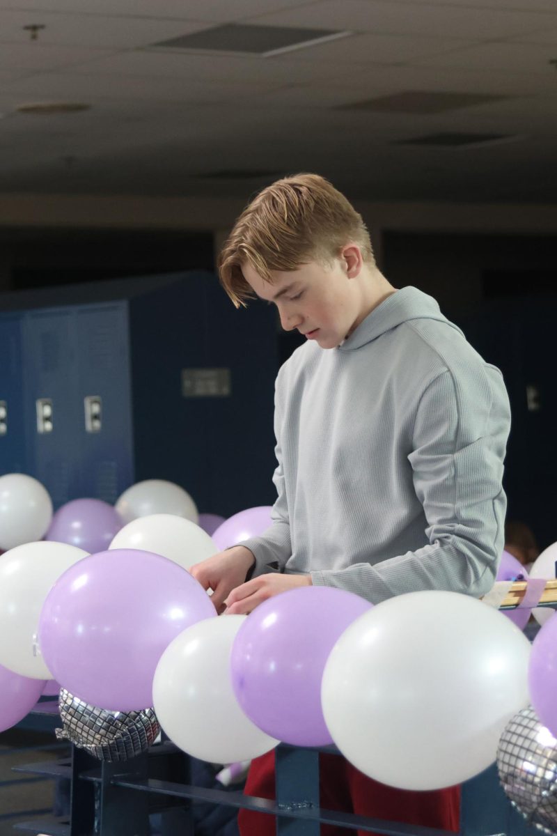 Freshman Calton Bierl uses string to tie inflatable disco balls and balloons during Relay for Life's Purple Bomb. 