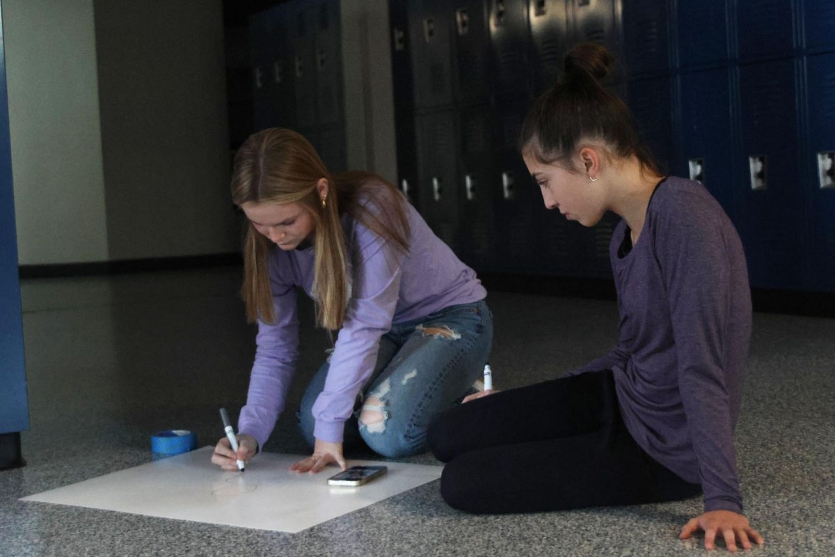 Freshmen Paige Lowe and Cortlyn Peterson use markers to design a hero themed poster for Relay for Life's Purple Bomb on January 20. 