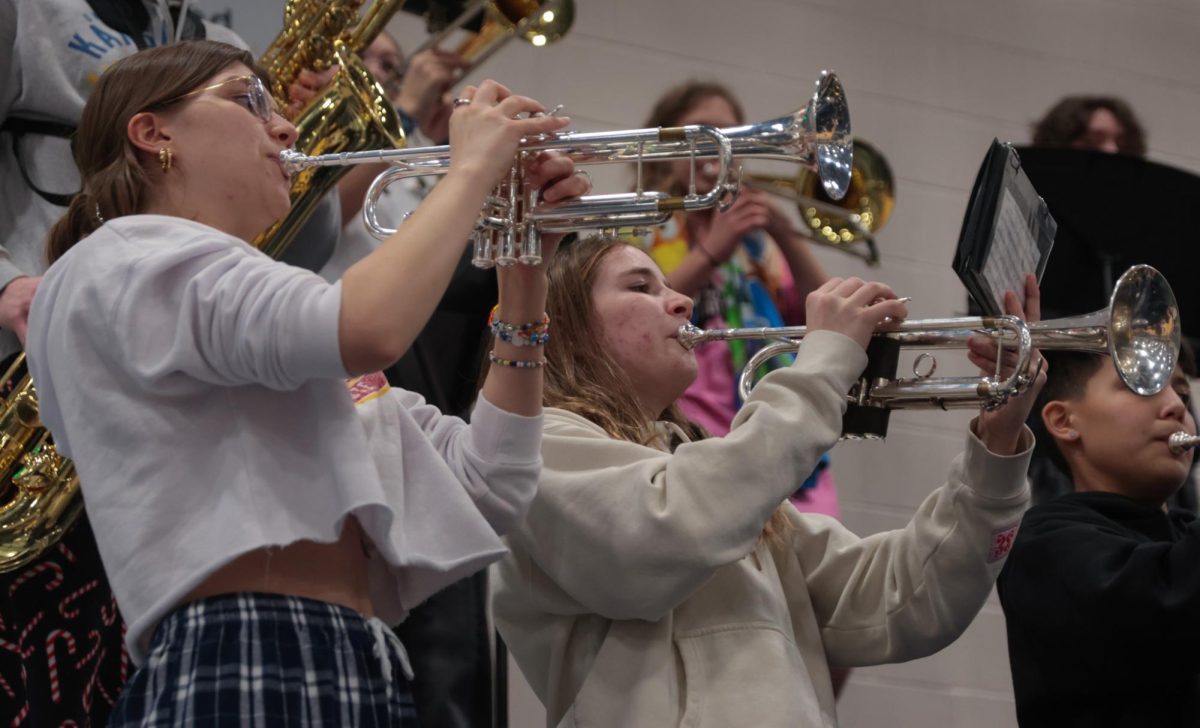 In tandem, sophomore Autumn Anderson and senior Joah Clark play their trumpets to the beat.
